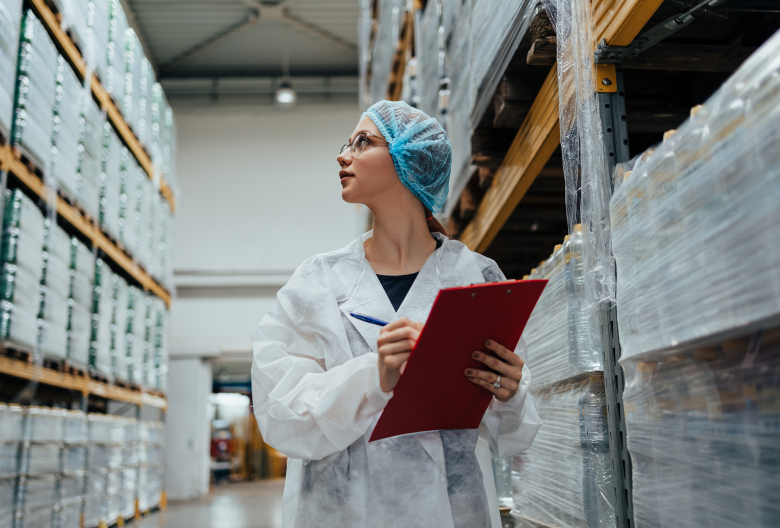 Woman wearing a clean suit with a clipboard in a warehouse
