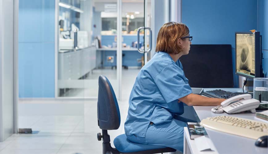 A veterinarian sits in her office using practice management software on her office computer