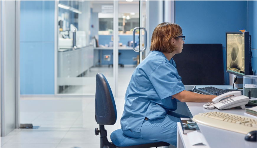 A veterinarian sits in her office using practice management software on her office compute