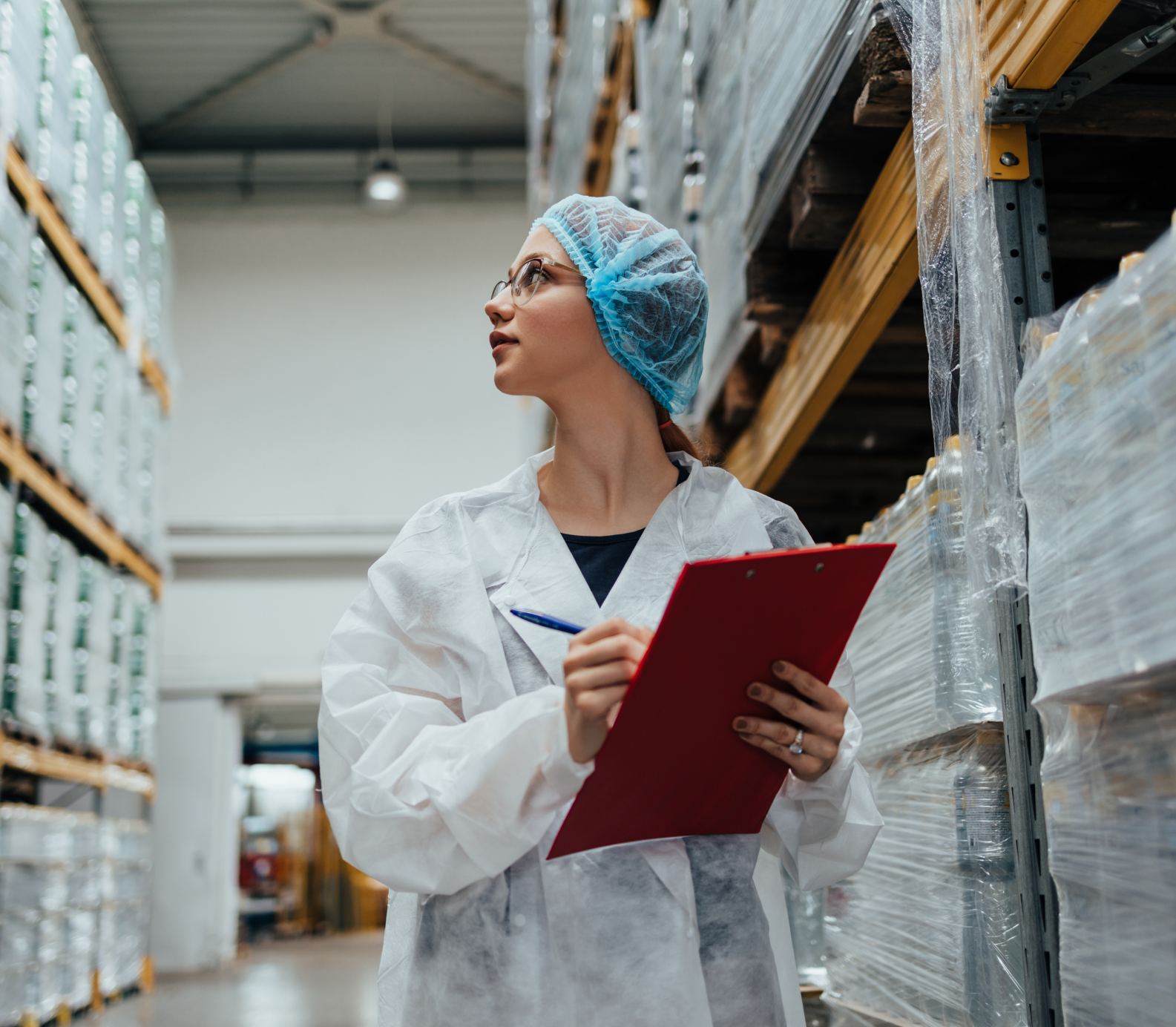 A person with a clipboard wearing a clean suit in a warehouse