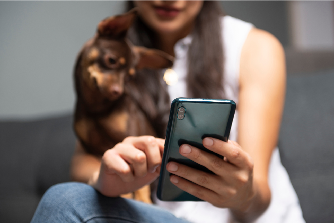 Woman looking at a smartphone with a dog on her lap