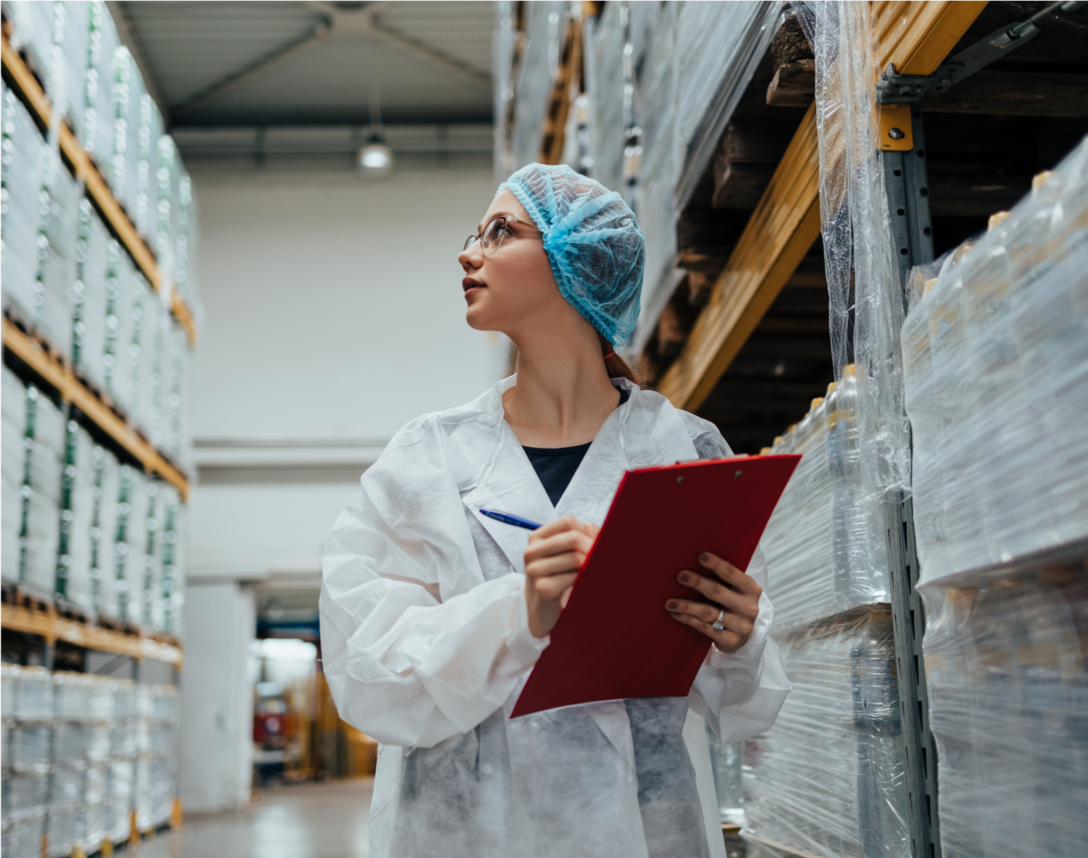 A person with a clipboard wearing a clean suit in a warehouse