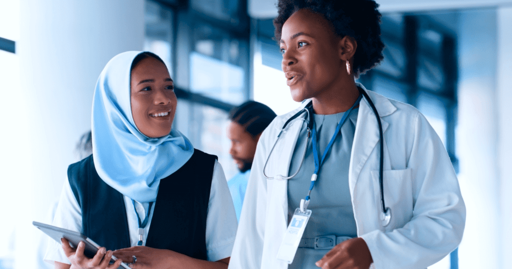 Two young veterinarians talking while walking, one carrying a tablet.