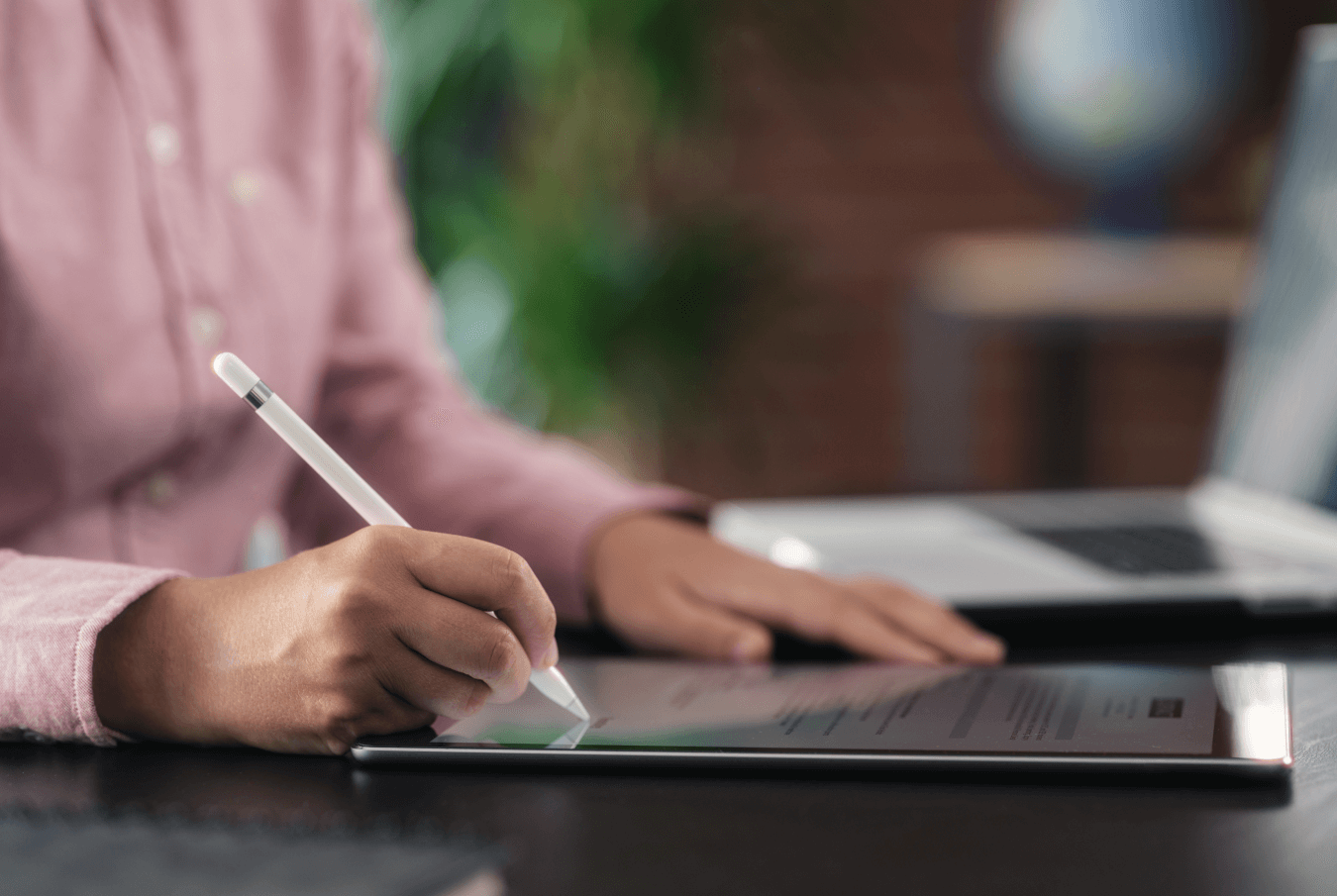 Closeup of a person’s hand writing on a tablet with a stylus