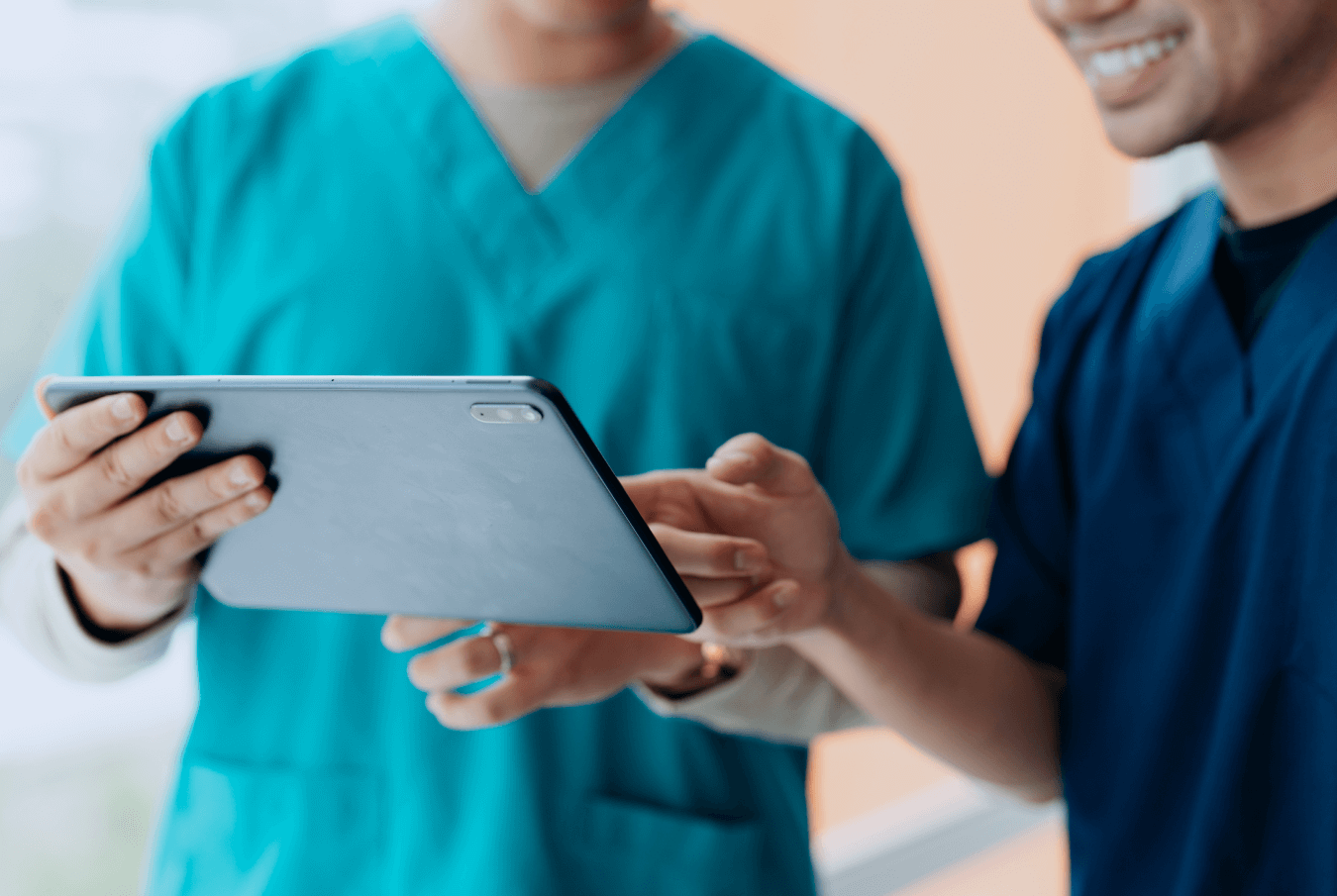 Two vet techs smiling while looking at a tablet.