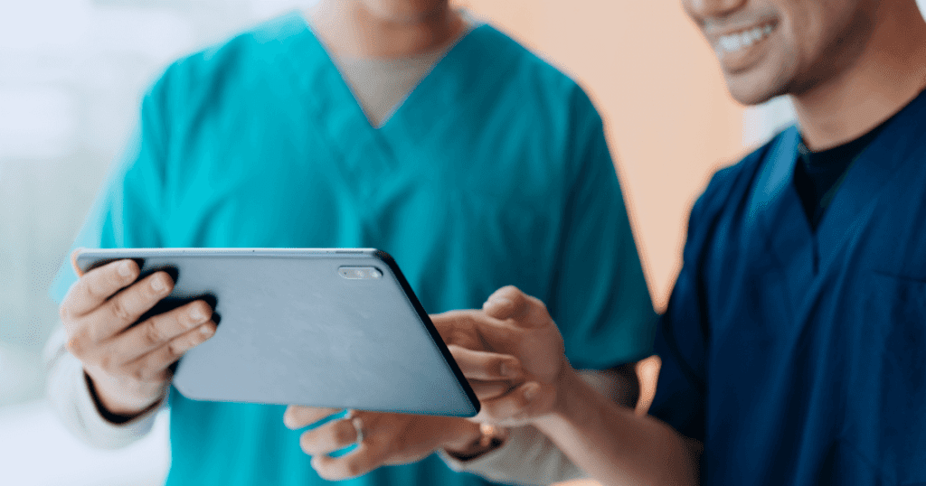 Two vet techs smiling while looking at a tablet.