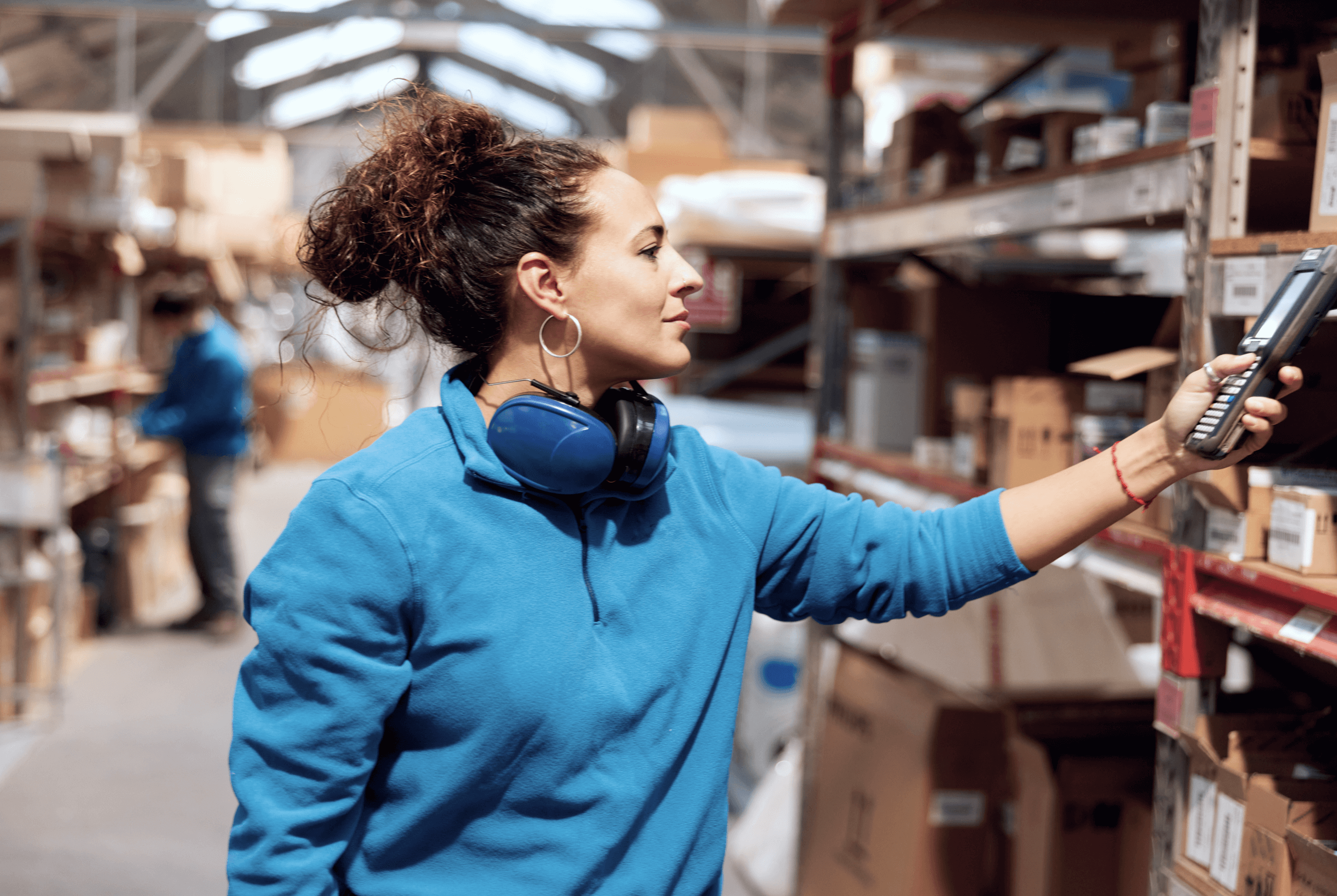 A female warehouse worker scanning inventory with a handheld scanner.