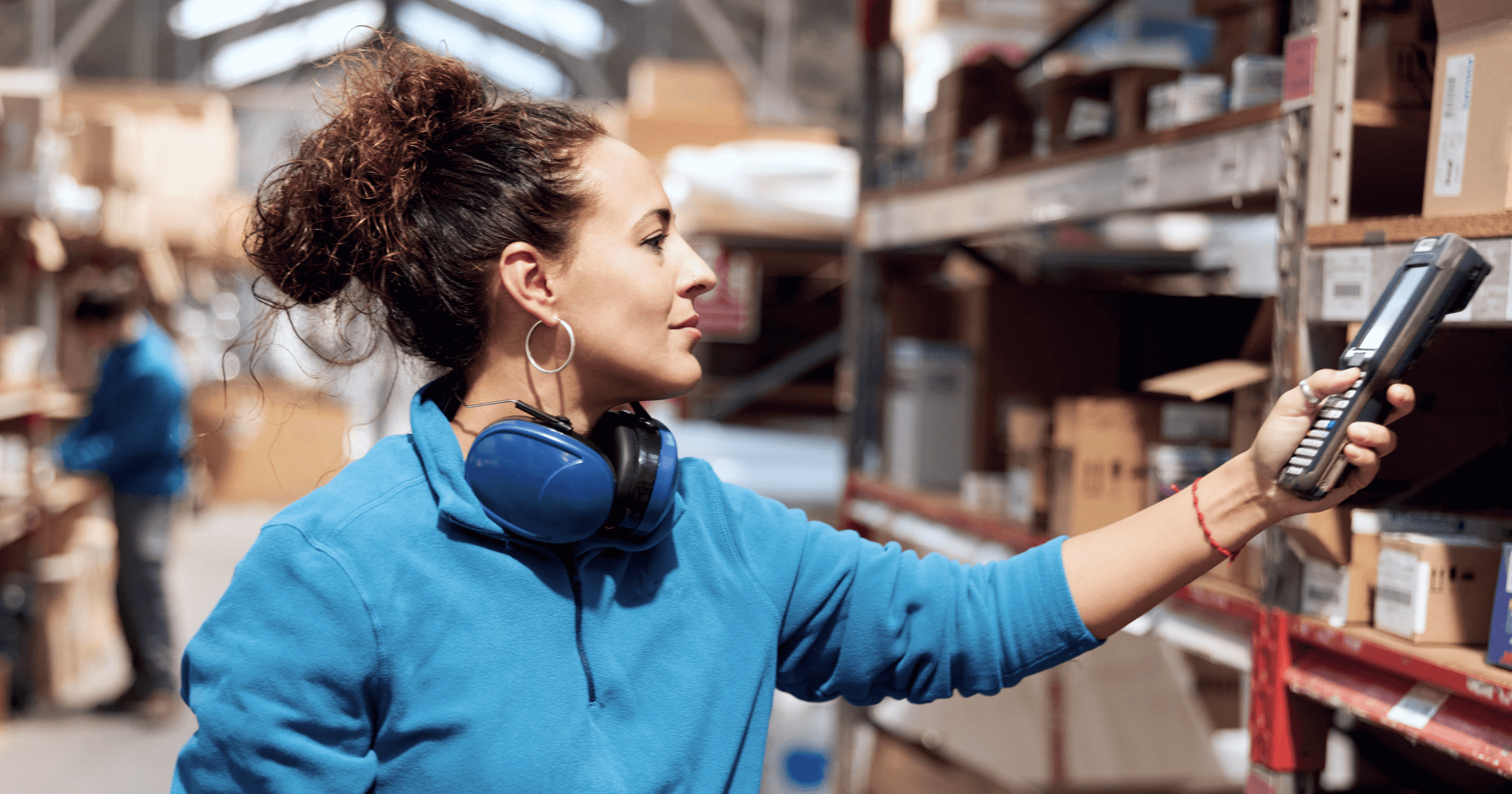 A female warehouse worker scanning inventory with a handheld scanner.