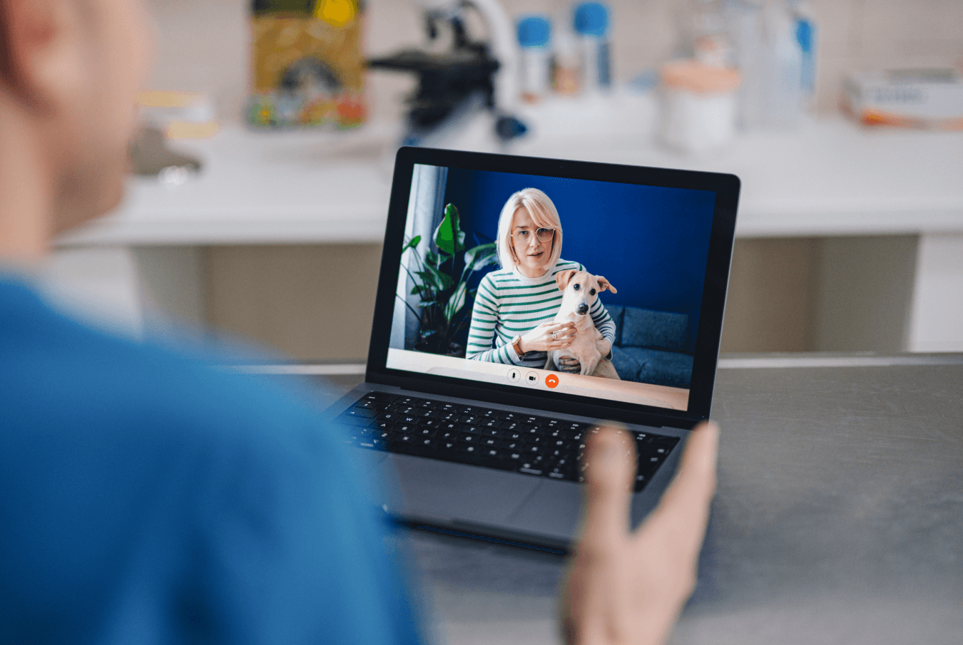 Looking over a veterinarian’s shoulder as they conduct a telemedicine session with a pet parent and their dog