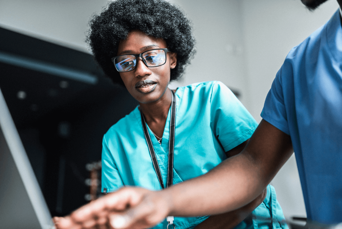 A young female vet tech studying a screen while a colleague points to it in the foreground.