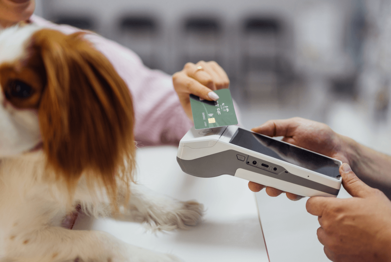 Pet owner with her dog making a credit card payment on a mobile point-of-sale device