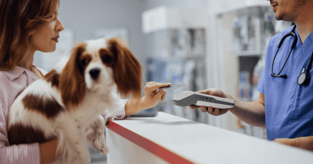 Woman pet owner carrying her cavalier king charles spaniel and making a credit card payment