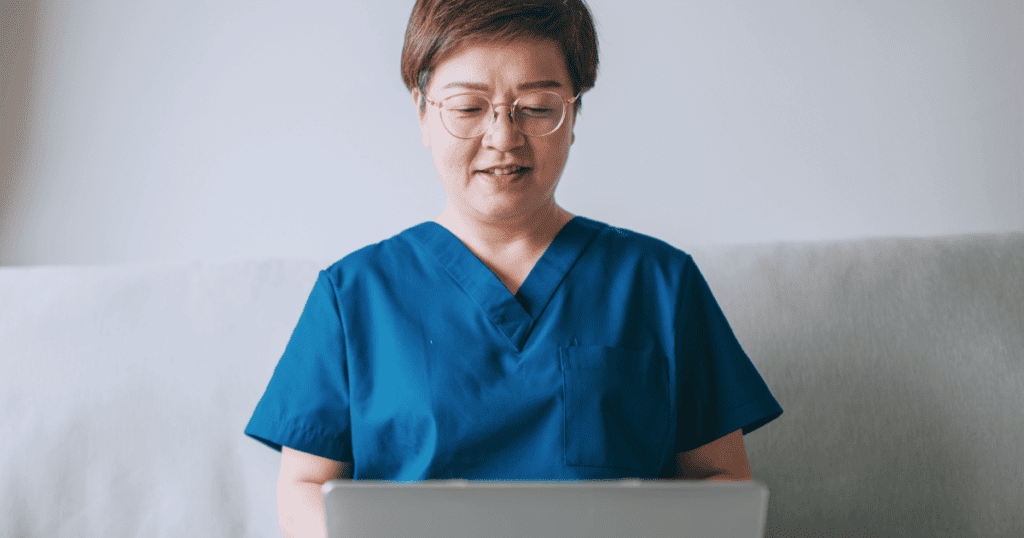 Female vet wearing glasses typing into her laptop sitting on a white couch