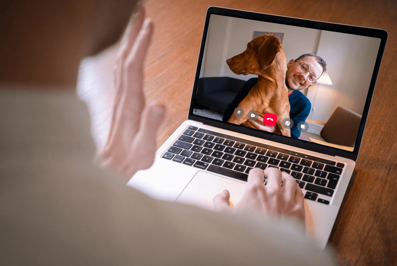 Vet holding a teleconference on a laptop with a pet owner and his dog