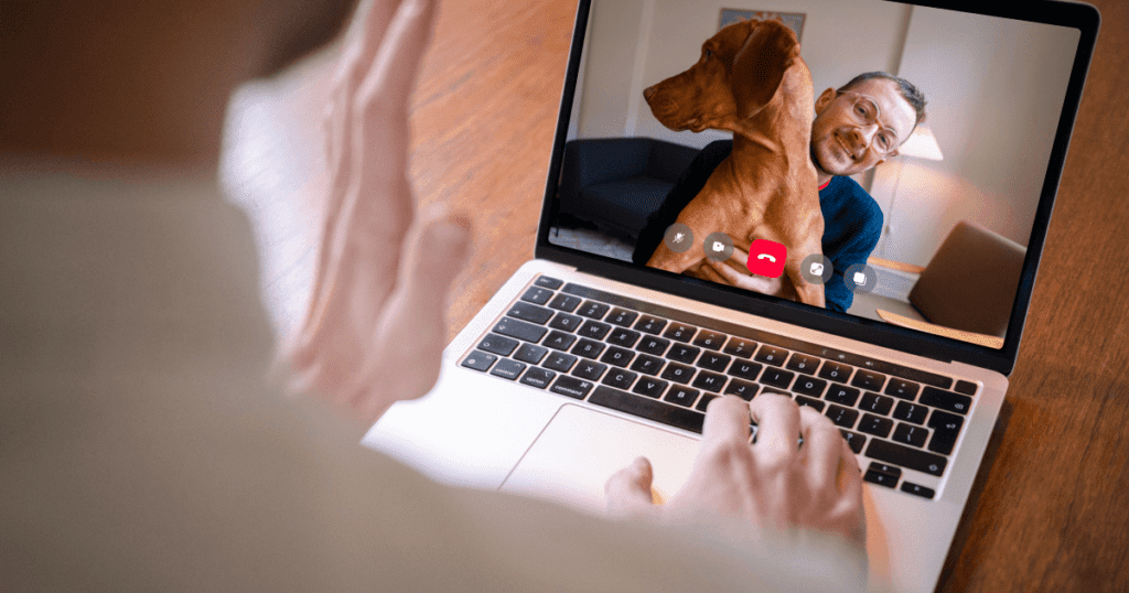 Vet holding a teleconference on a laptop with a pet owner and his dog