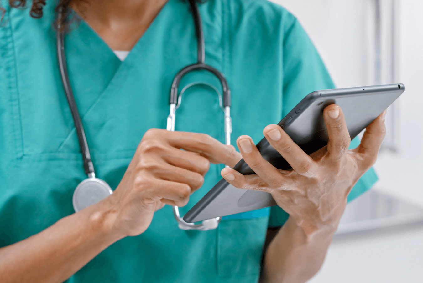 Vet with stethescope around her neck entering data into a tablet