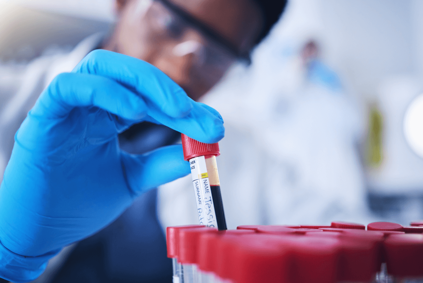 Vet tech pulling a blood sample in a vial from a tray