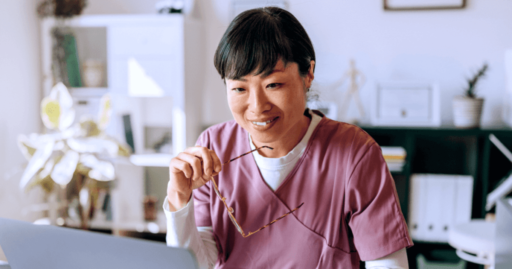 Smiling vet removing glasses while looking at data on her laptop screen