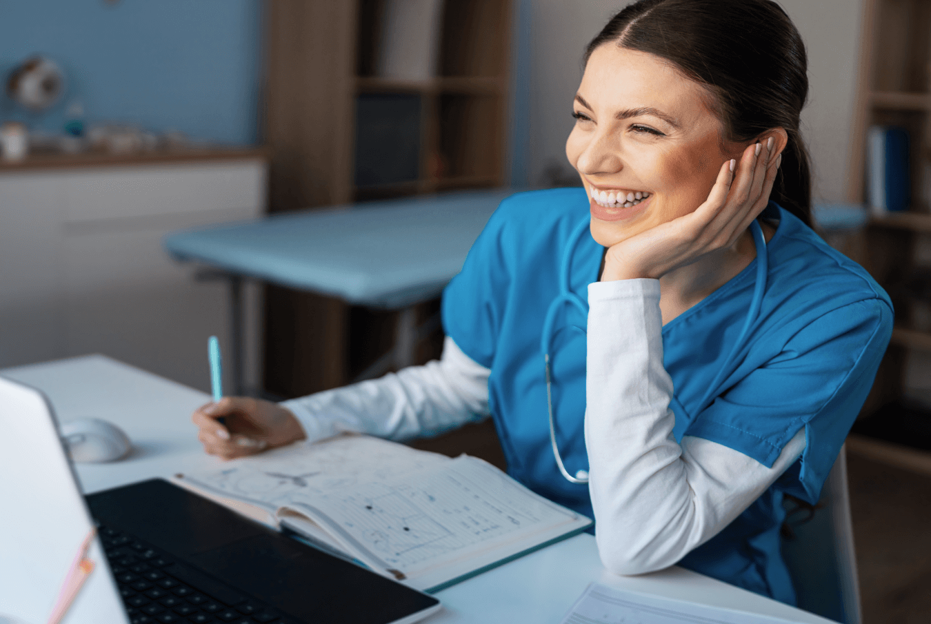 Young vet smiling and writing at her laptop computer