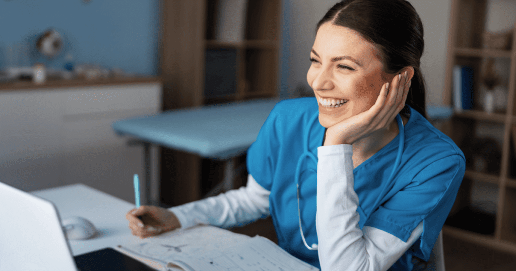 Young vet smiling and writing at her laptop computer