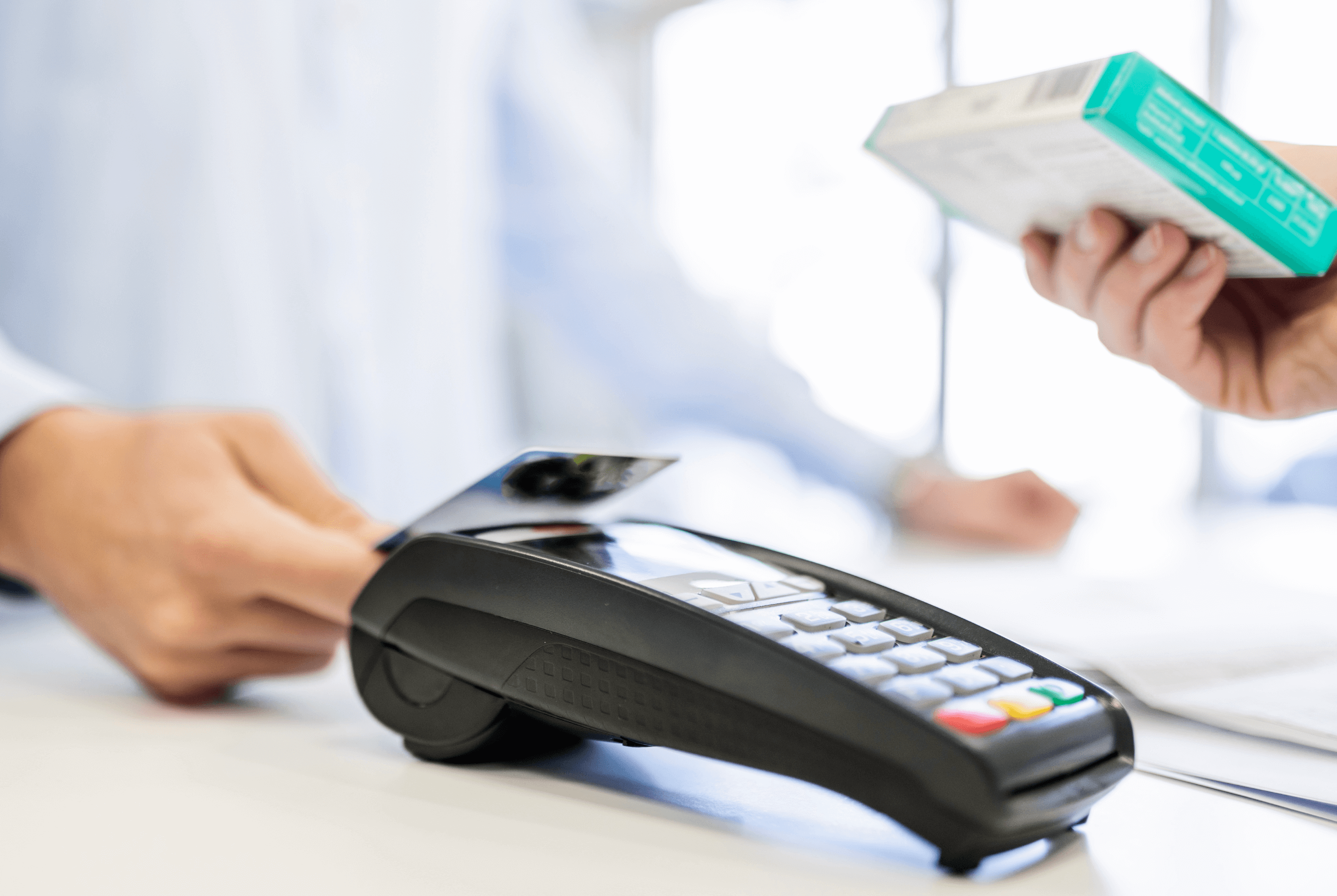 A customer paying for veterinary medication with a credit card tap, with the person handing them the medication in the foreground