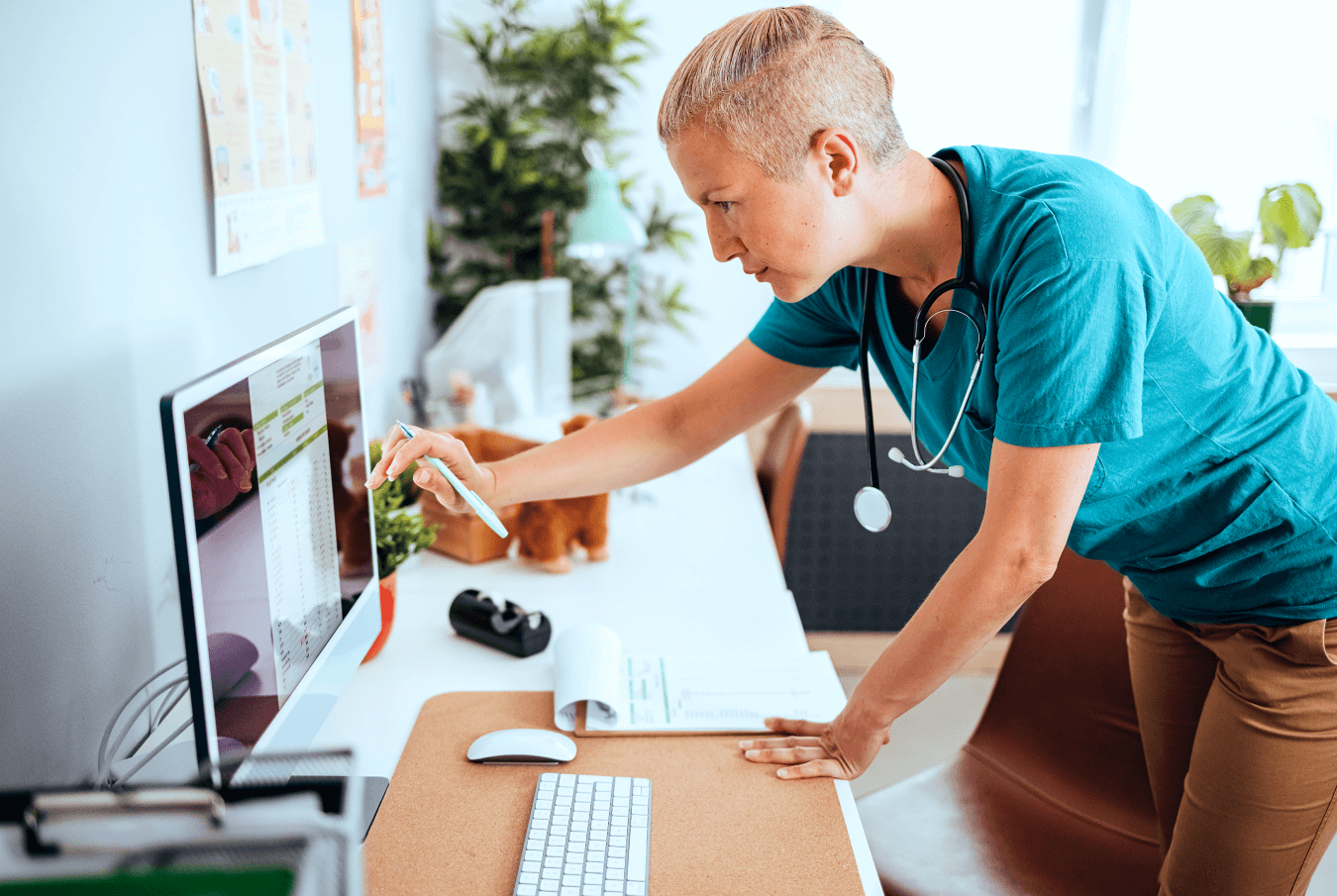 Woman vet standing in front of a desktop computer entering data into a touch screen monitor