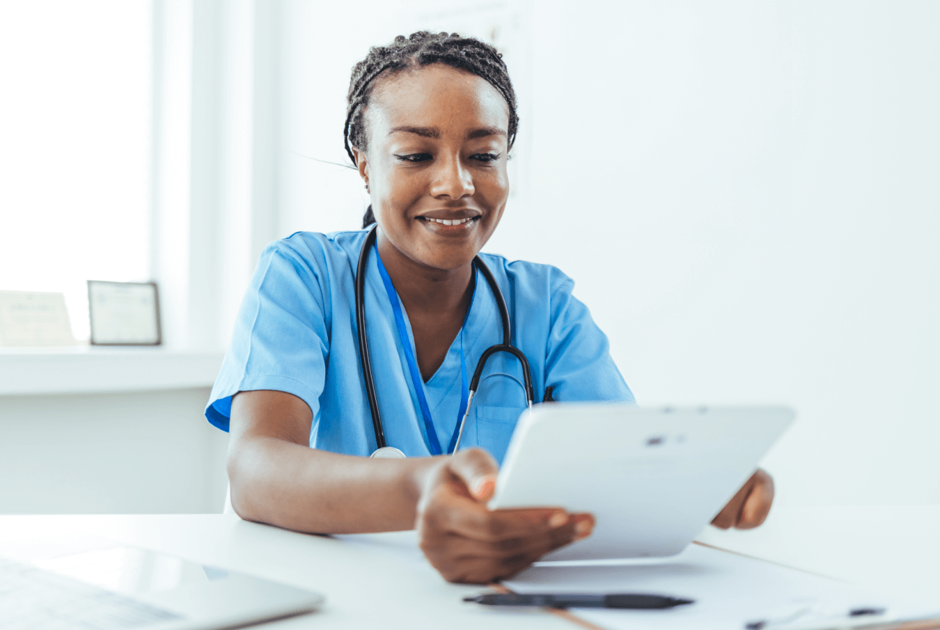 Smiling vet sitting at her desk checking her tablet in a modern office