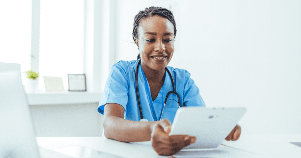 Smiling vet sitting at her desk checking her tablet in a modern office